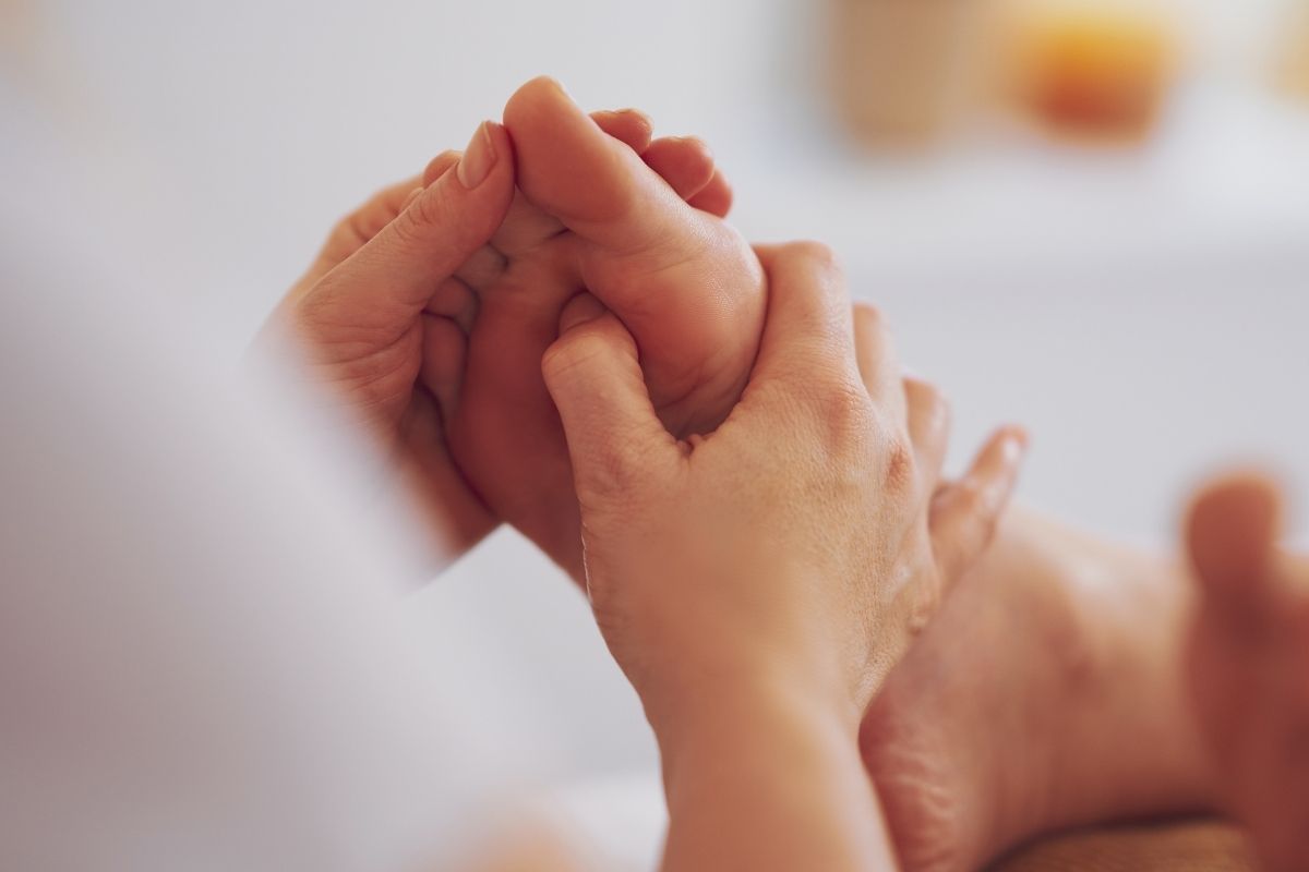 Close-up of a therapist's hands pressing reflexology points on the sole of a guest's foot at a Chinatown foot massage spa