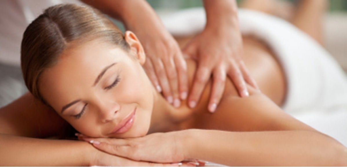 Guest smiling with eyes closed while a therapist works across her upper back during a treatment